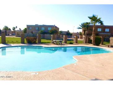 A community pool is surrounded by mature landscaping and overlooks multiple buildings at 4424 E Pueblo Ave, Phoenix, AZ 85040