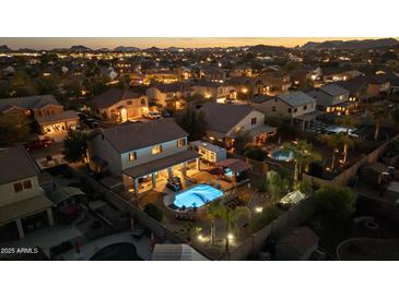 Stunning aerial view of a home with a private pool and lush backyard at dusk at 586 E Stirrup Ln, San Tan Valley, AZ 85143