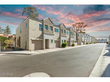 Charming townhomes with attached garages and attractive architectural details against a colorful sky at 8255 N 22Nd Dr, Phoenix, AZ 85021