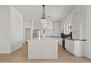 Modern kitchen with white cabinets, stainless steel appliances, and a large center island at 18344 W Santa Irene Dr, Goodyear, AZ 85338