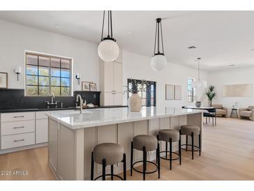 Bright, open kitchen features a large island with marble countertop and stylish pendant lighting at 18344 W Santa Irene Dr, Goodyear, AZ 85338