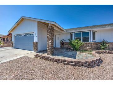 Charming single-story home with a stone facade, well-maintained landscaping, and attached garage under a clear blue sky at 3728 E Grove Ave, Mesa, AZ 85206