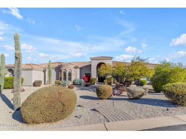 Stunning desert home featuring a stone accent and a meticulously landscaped front yard with mature plants and cacti at 6938 E Lomas Verdes Dr, Scottsdale, AZ 85266