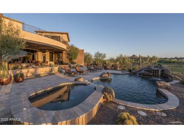 A luxurious pool with spa, waterfall feature, stone accents, and patio furniture overlooks the Arizona landscape at 9161 E Superstition Mountain Dr, Gold Canyon, AZ 85118