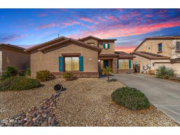Charming single Gathering home featuring desert landscaping, blue shutters, and a well maintained lawn at 18060 W Rimrock St, Surprise, AZ 85388