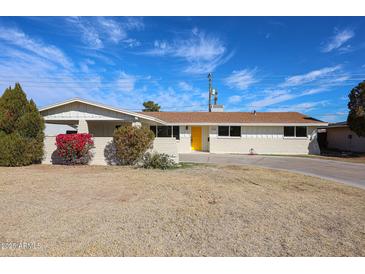 Charming single-story home features a vibrant yellow door and well-manicured landscaping, complete with a large driveway at 3716 W Griswold Rd, Phoenix, AZ 85051