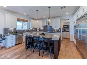 A modern kitchen featuring white cabinets, stainless steel appliances, and a large island with bar seating at 4306 E Flower St, Phoenix, AZ 85018