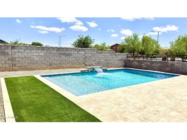 Sparkling pool with water feature, stone surround, and artificial turf, perfect for relaxation and outdoor enjoyment at 5345 W Leodra Ln, Laveen, AZ 85339
