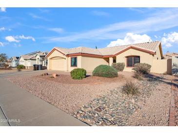 Single-story home with a desert landscape, complemented by a tan exterior and tile roof, perfect for low-maintenance living at 8736 W Kathleen Rd, Peoria, AZ 85382