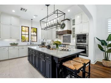 Bright kitchen features white cabinets, black island, marble countertops, stainless appliances and a large island at 9412 E Hidden Spur Trl, Scottsdale, AZ 85255