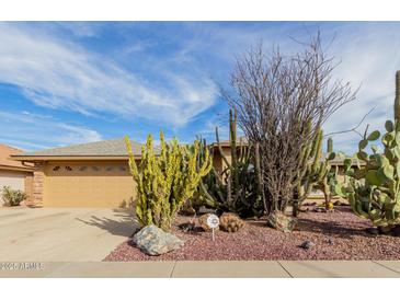 Beautiful desert landscaping surrounds the home and complements the tan exterior and brown two car garage at 11530 E Monterey Ave, Mesa, AZ 85209