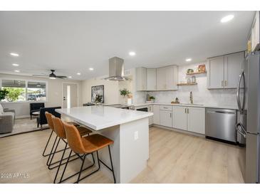 Modern kitchen with white countertops, stainless steel appliances and breakfast bar with three chairs at 13446 N 18Th Ave, Phoenix, AZ 85029