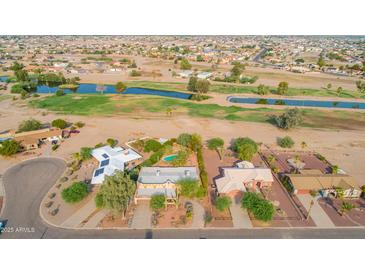 Expansive aerial view showcasing houses near a golf course with serene water features and lush greenery at 14264 S Baniff Ln, Arizona City, AZ 85123