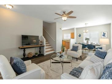 Inviting living room featuring hardwood floors, a ceiling fan, and stairs leading to the second floor at 16219 W Woodlands Ave, Goodyear, AZ 85338