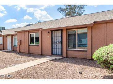 Modest one-story home with a light brown exterior, a black security door, and a well-maintained front yard at 3645 N 69Th Ave # 67, Phoenix, AZ 85033