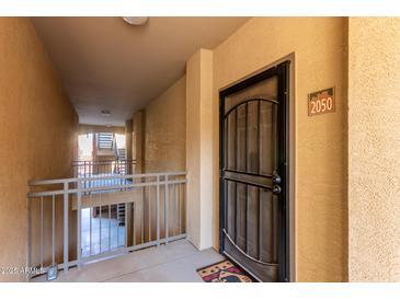 Inviting condo entrance with security door, neutral colors, and nearby staircase access at 5401 E Van Buren St # 2050, Phoenix, AZ 85008