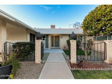 Welcoming front entrance features a walkway and a charming brick wall, complete with lush landscaping and a vibrant tree at 10808 W Kelso Dr, Sun City, AZ 85351