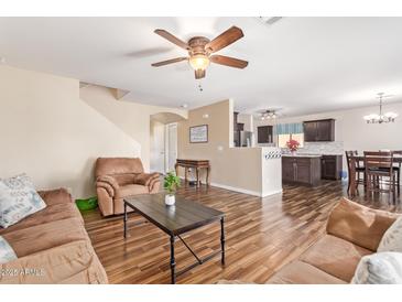 Open-concept living room with staircase, wood-look flooring, and comfortable sofa and armchair at 317 W Settlers Trl, Casa Grande, AZ 85122