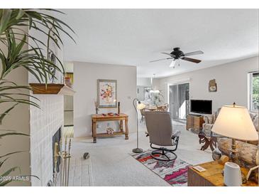 Bright living room featuring fireplace, ceiling fan, and access to dining area with natural light from sliding glass door at 5525 E Thomas Rd # O8, Phoenix, AZ 85018