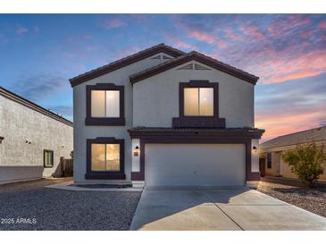 Charming two-story home with a two-car garage and well-maintained landscaping under a beautiful sunset sky at 11457 W Madisen Ellise Dr, Surprise, AZ 85378