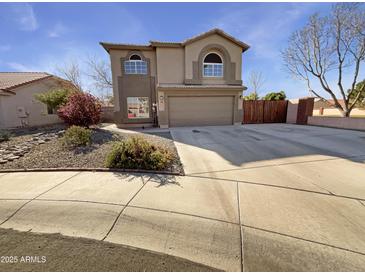 Two-story home with desert landscaping, a two-car garage, and neutral earth tone paint at 11595 W Holly St, Avondale, AZ 85392