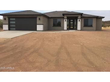 New construction home with desert landscaping, modern garage door and stone accents at 17030 W Whispering Rock Trl, Surprise, AZ 85387