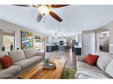 Open-concept living room flows to kitchen, showcasing modern decor and natural light from sliding glass door at 1846 N Sunview --, Mesa, AZ 85205