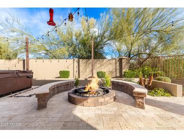 Inviting backyard featuring a stone fire pit with seating and mature landscaping at 22905 N 19Th Way, Phoenix, AZ 85024