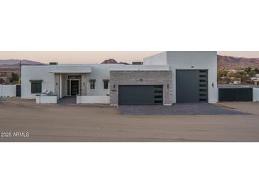 Modern home featuring a clean white design with gray garage doors, brick accents, and mountain views at 37931 N 31St Ave, Phoenix, AZ 85086