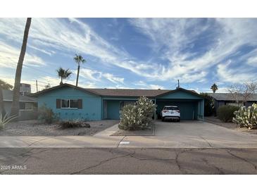 Charming single-story home featuring a desert landscape, covered parking, and a blue-painted exterior at 6413 E Holly St, Scottsdale, AZ 85257