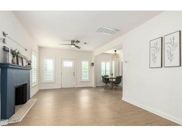 Bright living room featuring wood floors, neutral paint, a fireplace, a ceiling fan, and access to the dining area at 809 N 11Th Ave, Phoenix, AZ 85007