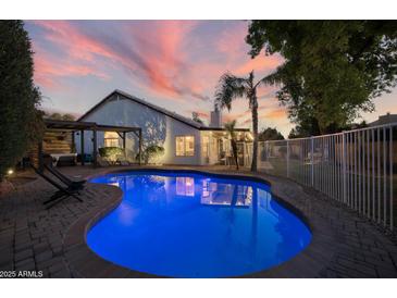 An inviting pool with a baja step and lush landscaping at twilight provides a tranquil outdoor oasis at 928 S San Joaquin Ct, Gilbert, AZ 85296