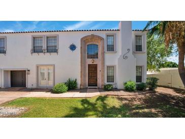 Charming two-story home featuring stucco siding, a terracotta roof, a manicured lawn, and a stylish front door at 111 W Missouri Ave # E, Phoenix, AZ 85013