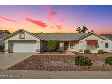 Charming single-story home with a two-car garage, desert landscaping, and a red awning at sunset at 13548 W Whitewood Dr, Sun City West, AZ 85375