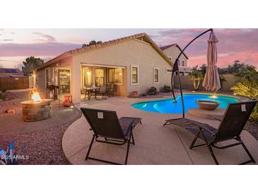 Resort-style pool and patio with a fire pit, comfortable lounge chairs, and an umbrella, perfect for outdoor relaxation at 16412 N 168Th Ln, Surprise, AZ 85388