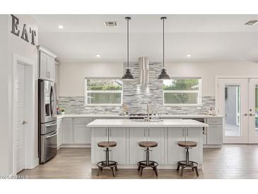 Bright kitchen with gray cabinets, stainless steel appliances, an island, and decorative backsplash at 3007 N 47Th St, Phoenix, AZ 85018