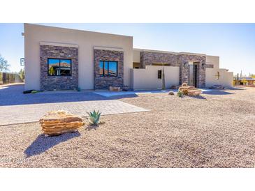 Beautiful modern home exterior featuring stone accents, desert landscaping, and a paver walkway at 5468 E Dove Valley Rd, Cave Creek, AZ 85331