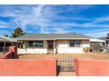 Charming single-story home with a decorative block wall, featuring a gray roof and well-lit, classic facade at 200 E Rose Ln, Avondale, AZ 85323