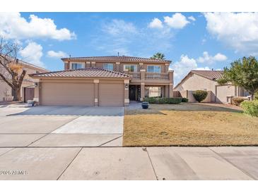 Two-story home with tile roof, balcony, three-car garage and manicured lawn on a sunny day at 2535 E Saratoga St, Gilbert, AZ 85296