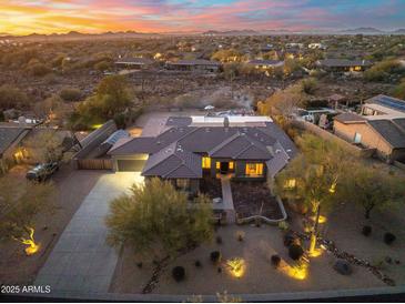 Stunning aerial view of desert home with a tile roof and circular drive surrounded by desert landscape and mountains at 27606 N 61St Pl, Scottsdale, AZ 85266