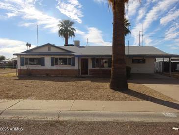 Charming single-story home with a carport, palm trees, and a desert landscape at 3345 W Laurel Ln, Phoenix, AZ 85029