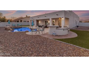 Backyard oasis featuring a pool, spa, outdoor kitchen, and covered patio with dining and seating areas at 3459 E Mockingbird Dr, Gilbert, AZ 85234