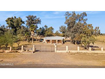 Charming single-story home featuring a gated entrance, desert landscaping, and a covered front porch with arched columns at 50880 W Val Vista Rd, Maricopa, AZ 85139