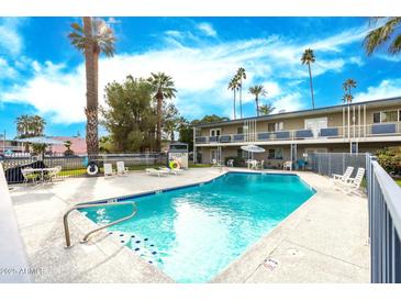 Refreshing pool with sun loungers and seating surrounded by palm trees and building at 6834 E 4Th St # 6, Scottsdale, AZ 85251