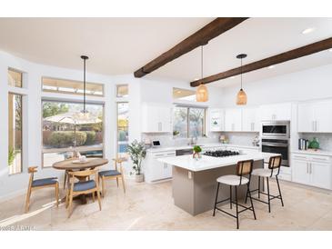 Open kitchen and breakfast nook featuring white cabinetry, kitchen island with seating, and views of the backyard and pool at 7357 E Rochelle Cir, Mesa, AZ 85207