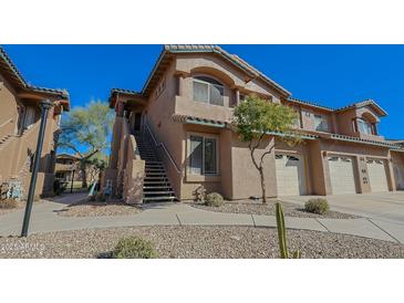 A charming two-story townhome shows southwest architecture, a front-entry staircase, a one-car garage, and a well-manicured xeriscaped front yard at 11500 E Cochise Dr # 2088, Scottsdale, AZ 85259