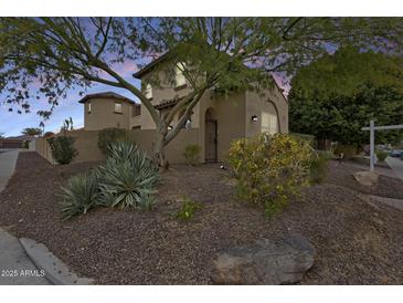 Charming two-story home with stucco facade, gated courtyard, and desert landscaping at dusk at 18256 W Carol Ave, Waddell, AZ 85355