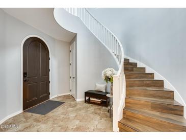 Inviting foyer featuring a curved staircase, tile flooring, and arched front door at 18256 W Carol Ave, Waddell, AZ 85355