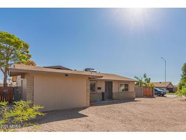 Tan single-story house with a gravel yard and brick accents under a clear blue sky at 1841 N Wilbur Cir, Mesa, AZ 85201