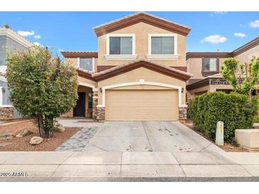 Two-story home featuring tan stucco, brown trim and stone accents around the garage with mature landscaping at 1911 E Hartford Ave, Phoenix, AZ 85022